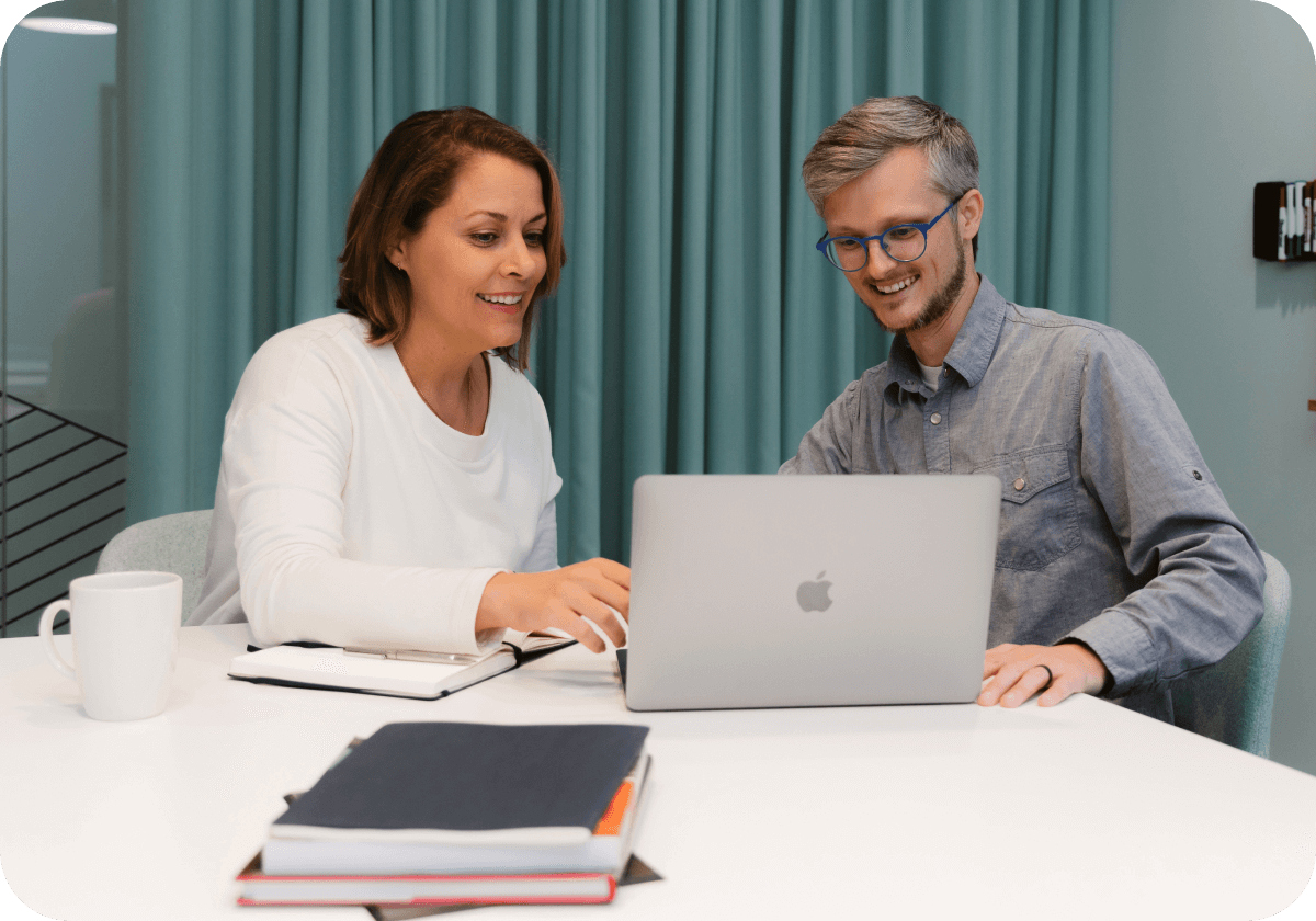 man and woman have friendly discussion over something on a laptop