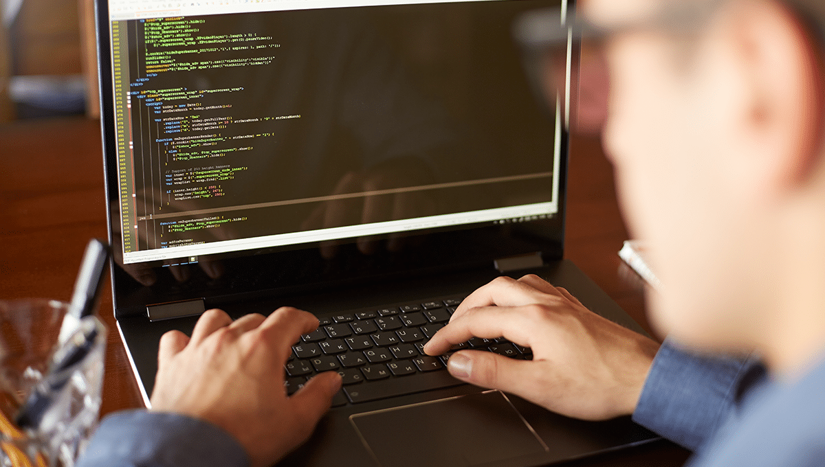 a man works on some code on a laptop